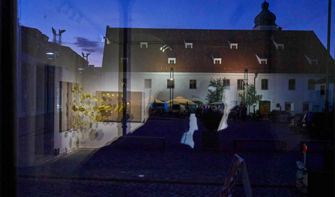 (c)HR ArchivNr: 882_220610_048 / 10.06.2022 / Ebersberg, Kunstverein, Vernissage Ausstellung Sabrina Sperl "knapp sichtbar". hier: Spiegelung Säulenhalle in Eingangstür mit Klosterbauhof und St. Sebastian